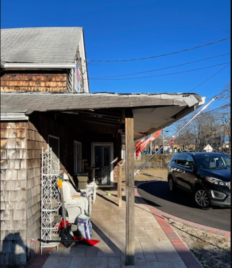 Before: sagging porch roof on weathered cedar siding