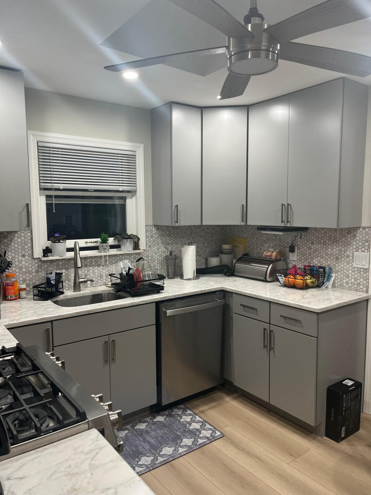 After: the sink wall with grey cabinets, white quartz counter, hexagon mosaic backsplash and a new faucet