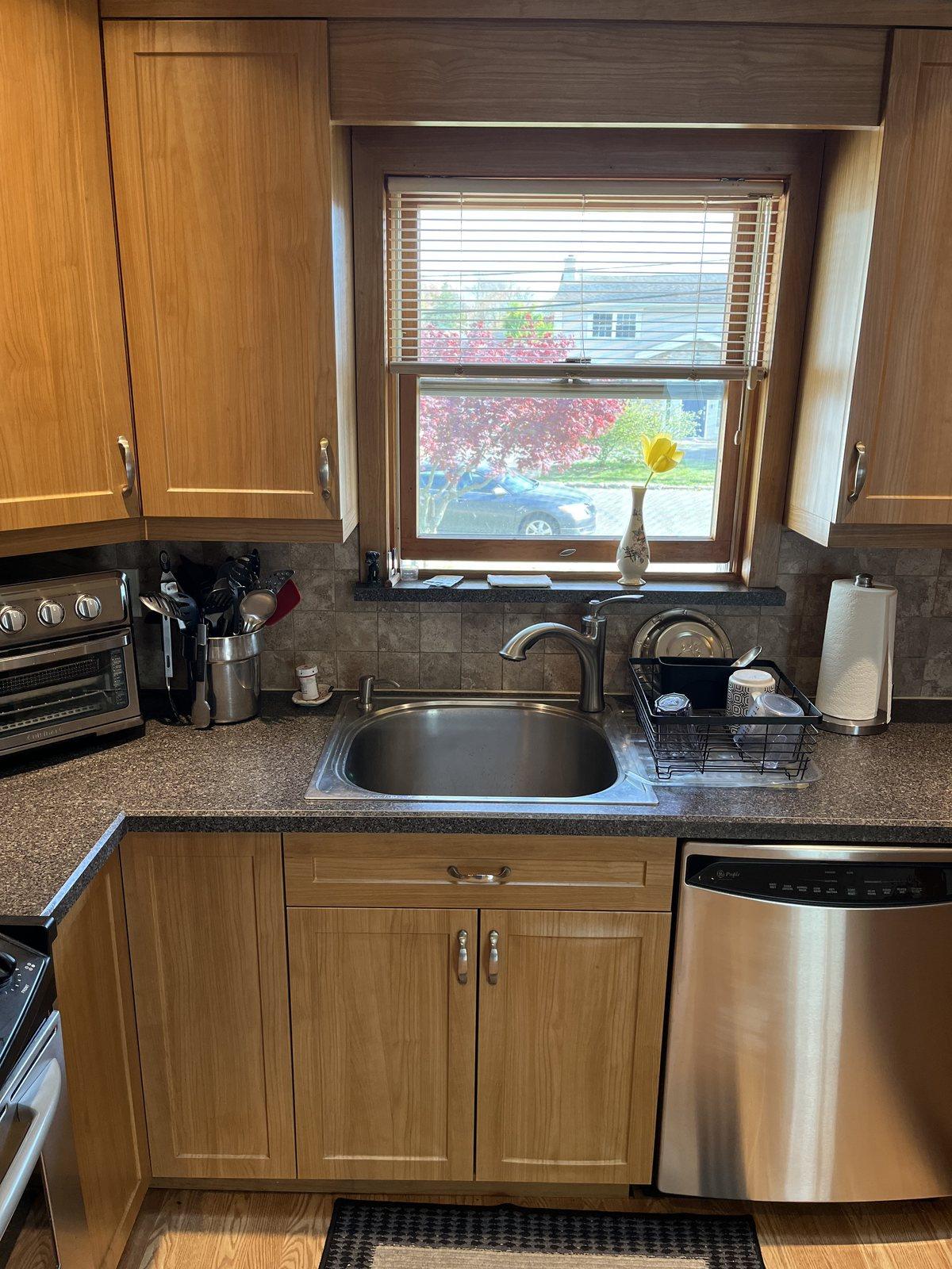 Before: the sink wall with oak cabinets, dark laminate counter and a small window