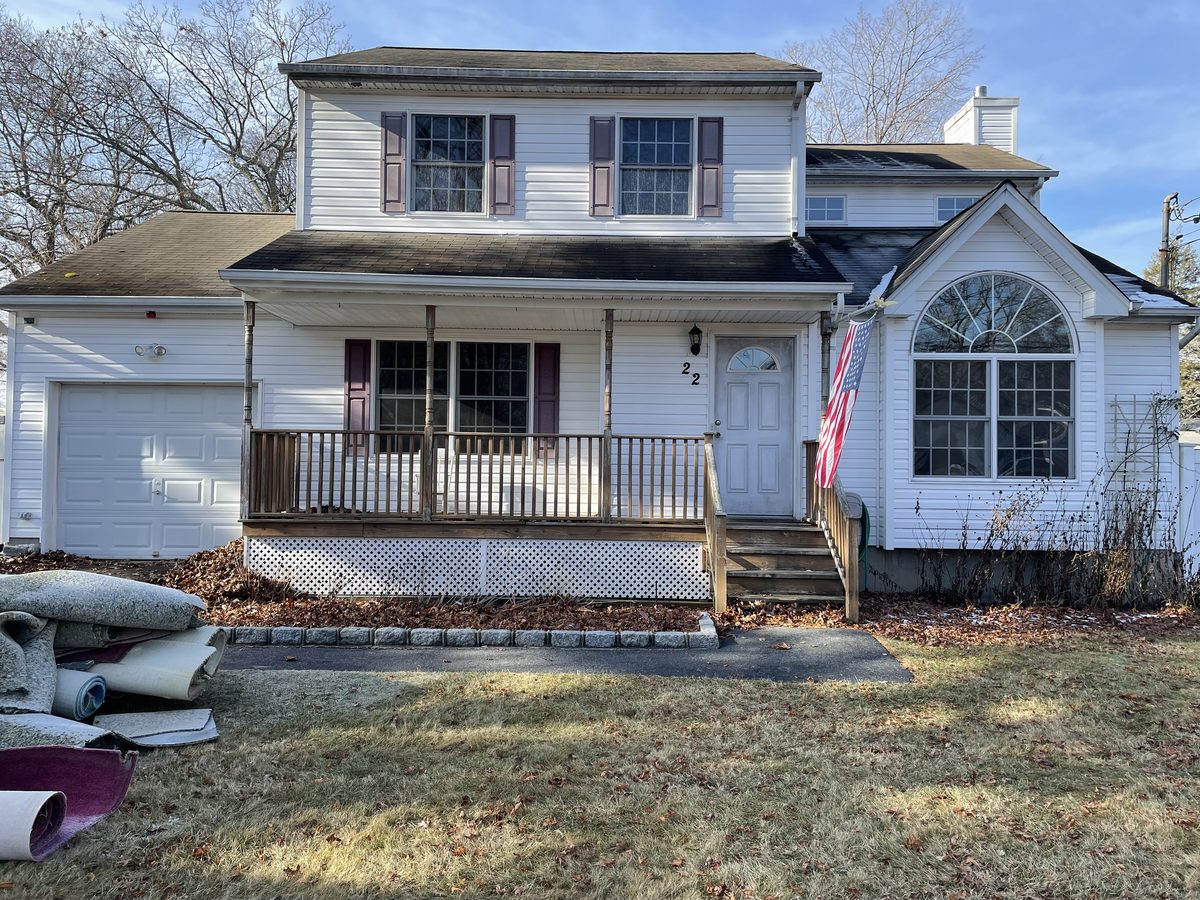 Before: the same Rocky Point colonial with a worn grey roof, a sagging wood porch and bare front yard