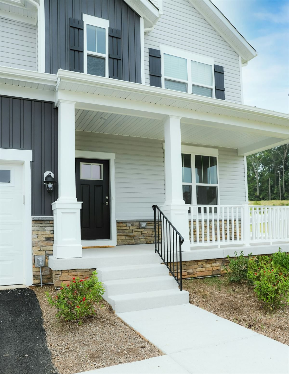 New black entry door and white-trimmed windows on a covered porch